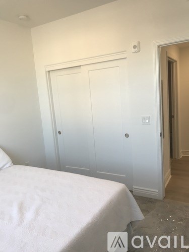 A white bedroom with a bed and a door.