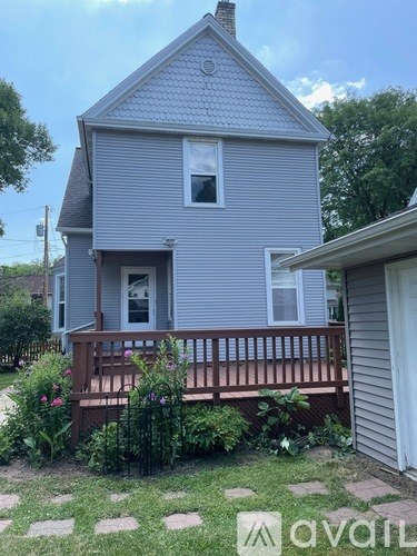 A house with a grey siding and a brown deck.
