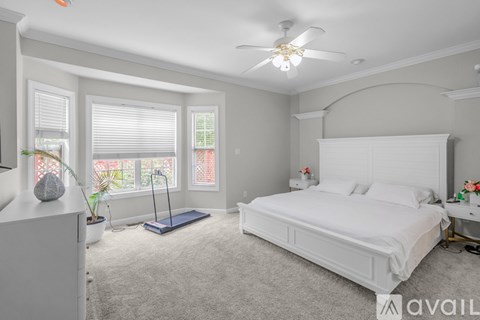 A bedroom with a large bed and a ceiling fan.
