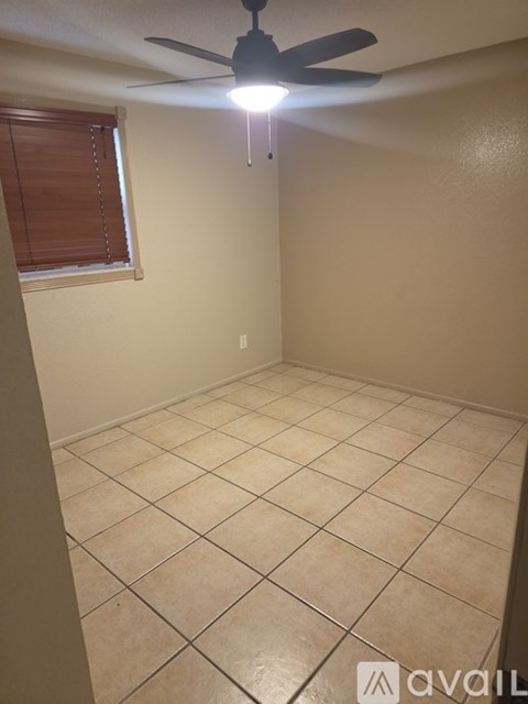A room with a ceiling fan and a window with blinds.