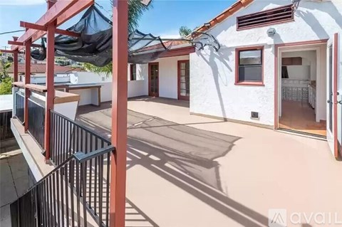 A balcony with a black railing and a white building with a red roof.