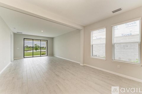A spacious room with a sliding glass door leading to a balcony.