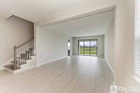 A spacious living room with a staircase and a view of the outdoors.