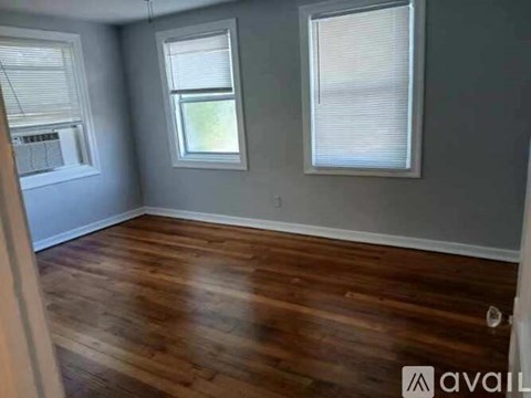 A room with wooden floors and two windows.