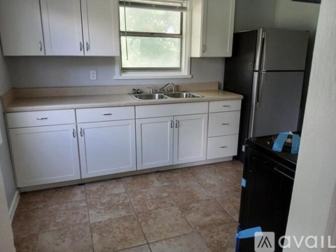 A kitchen with white cabinets and a black refrigerator.