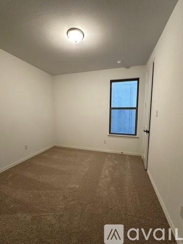 A room with a carpeted floor and a window.