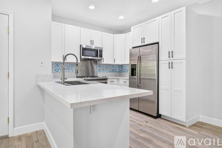 A kitchen with white cabinets and a white island.