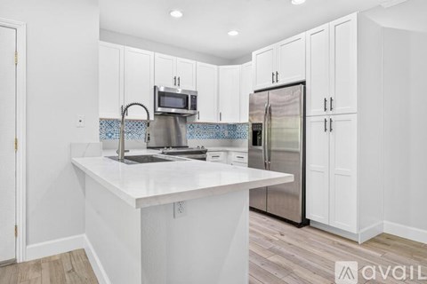 A kitchen with white cabinets and a white island.