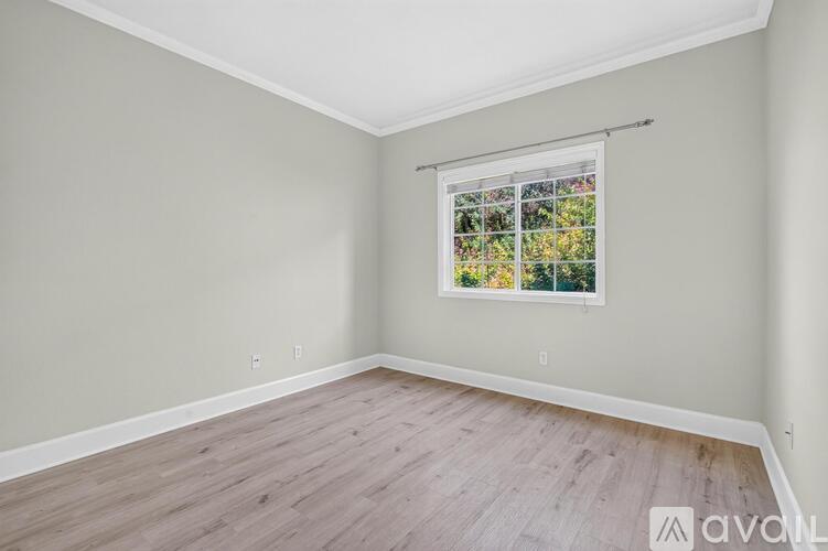 A room with a window showing a view of trees and flowers.