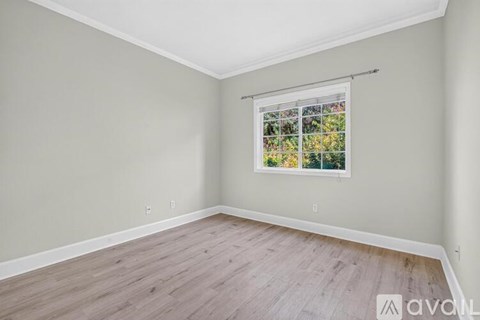 A room with a window showing a view of trees and flowers.