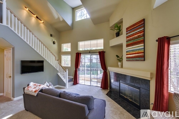 A living room with a grey couch and a fireplace.