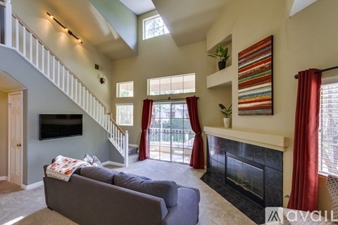 A living room with a grey couch and a fireplace.
