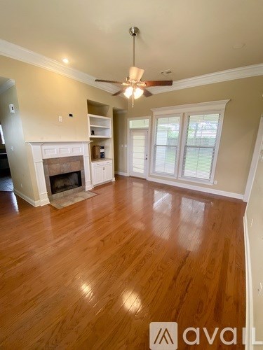 A living room with a fireplace and a ceiling fan.