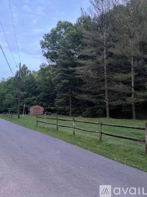 A road with a wooden fence and trees on the side.