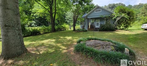 A house with a front yard and a large tree.
