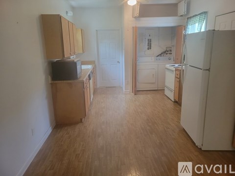 A kitchen with wooden floors and a white refrigerator.