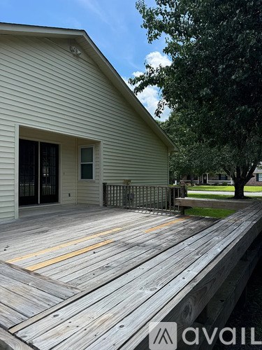 A wooden deck with a house and a tree in the background.