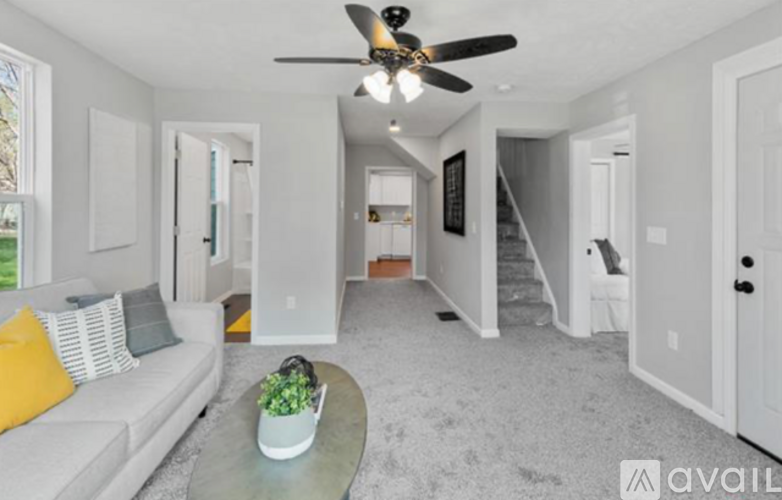 A living room with a grey couch and a ceiling fan.