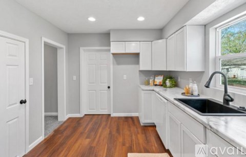 A kitchen with white cabinets and a wooden floor.