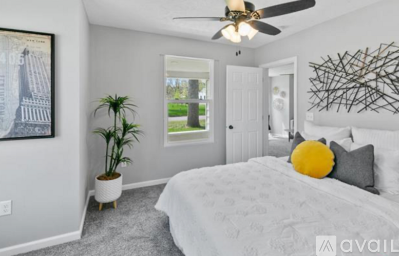 A bedroom with a bed, a ceiling fan, and a plant.
