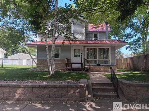 A house with a red roof and a porch with a bench.
