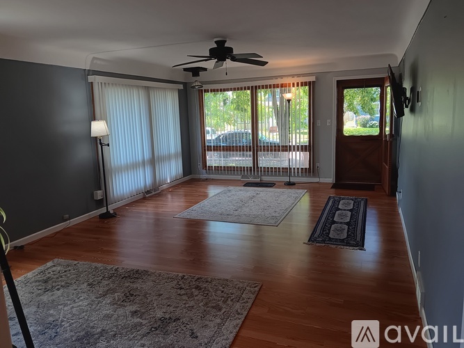 A room with a ceiling fan and sliding glass doors.