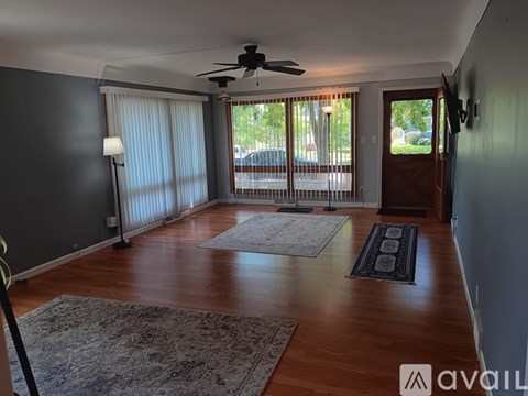 A room with a ceiling fan and sliding glass doors.