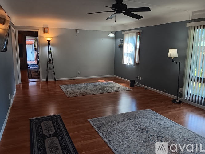 A living room with a ceiling fan and two windows.