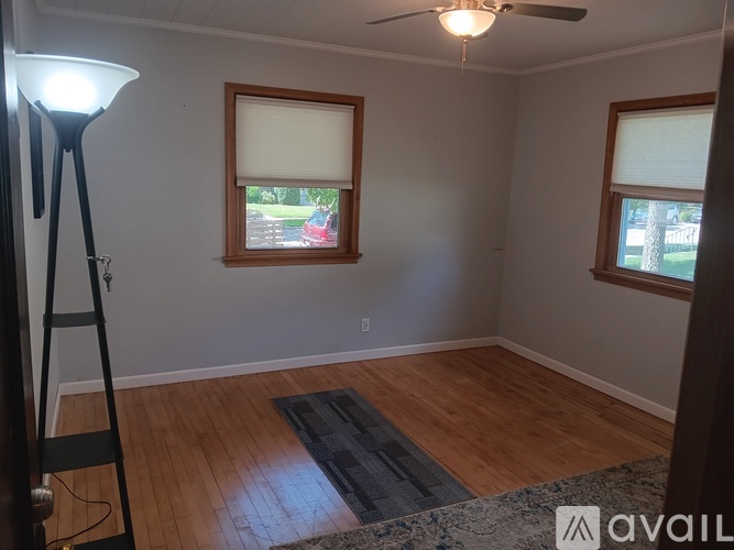 A room with a wooden floor and a rug in the middle.