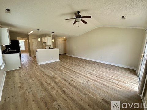 A spacious room with wooden flooring and a ceiling fan.