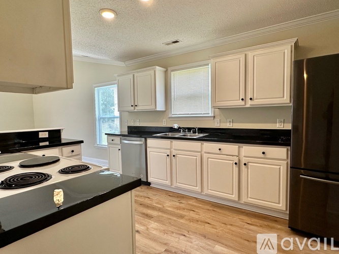 A kitchen with white cabinets and black countertops.