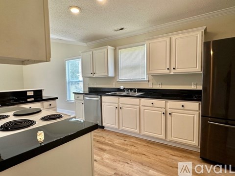 A kitchen with white cabinets and black countertops.
