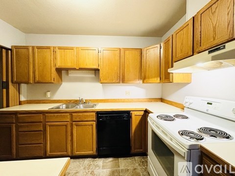 A kitchen with wooden cabinets and a white stove top oven.