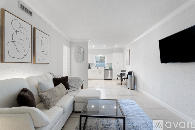 A living room with a white couch and a glass coffee table.