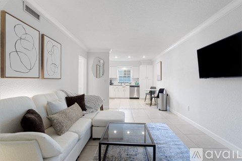 A living room with a white couch and a glass coffee table.