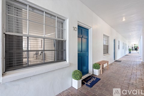 A long white building with a blue door and a mat on the ground.