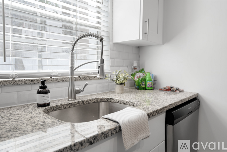 A kitchen with a sink and a window with blinds.