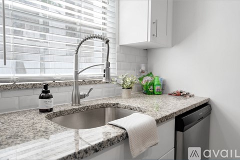 A kitchen with a sink and a window with blinds.