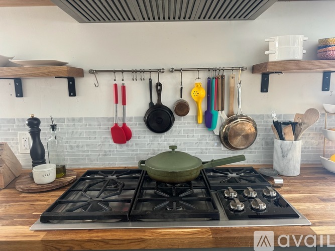 A kitchen with a black stove top and a white tiled backsplash.