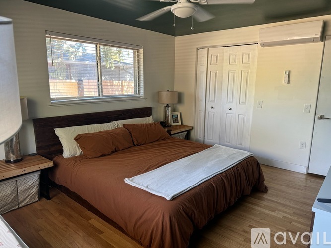 A bedroom with a bed, nightstand, and window.