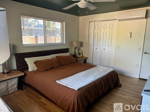 A bedroom with a bed, nightstand, and window.
