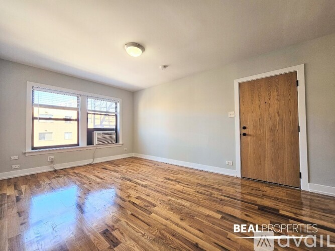 A room with a wooden floor and a door on the right side.