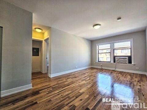 A room with wooden flooring and a window with blinds.
