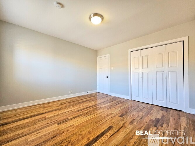 A room with wooden floors and white walls, with a white door on the right side.