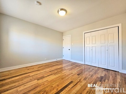 A room with wooden floors and white walls, with a white door on the right side.