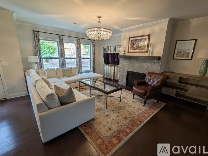 A living room with a white couch, a glass coffee table, and a fireplace.