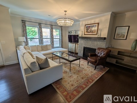 A living room with a white couch, a glass coffee table, and a fireplace.