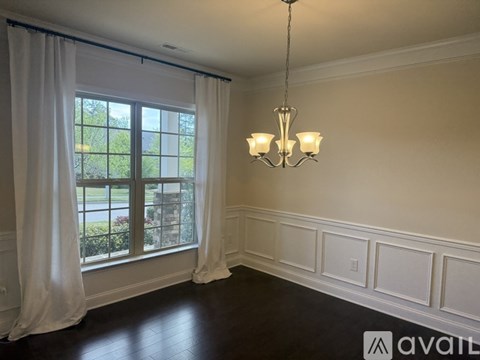 A room with a window, curtains, and a chandelier.