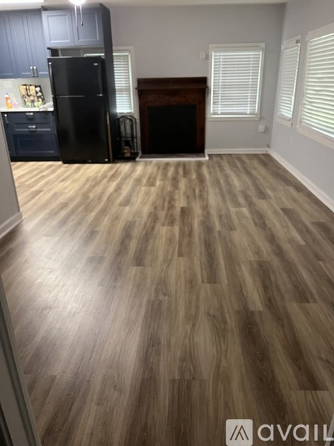 A kitchen with a black fridge and wooden flooring.