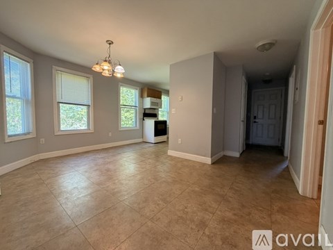 A spacious room with tiled flooring and a chandelier.